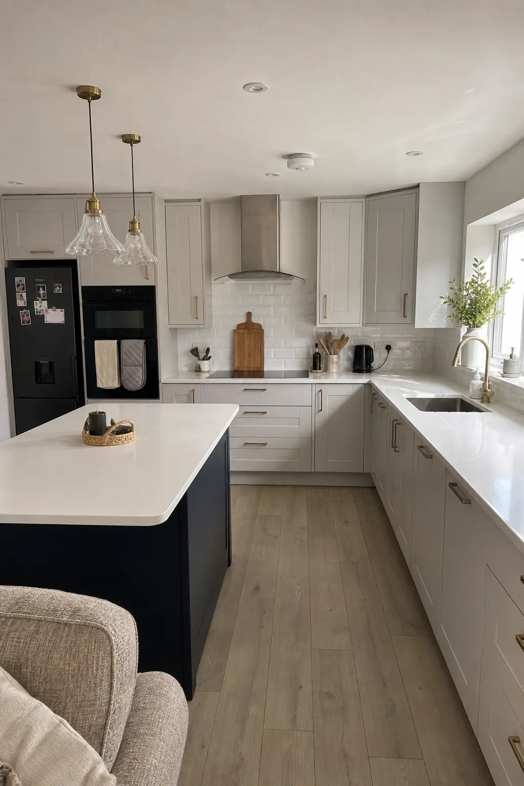 Pale grey shaker kitchen with a navy island, white worktops and brass pendant lights